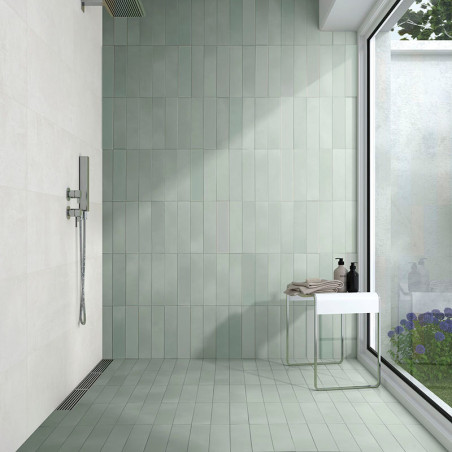 Un espace douche met en valeur des carreaux verts verticaux au mur et au sol, bordé par une grande baie vitrée donnant sur un ja