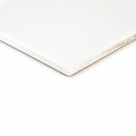 Un carreau de céramique blanche aux bords lisses repose sur un fond uni et clair, mettant en valeur sa surface brillante et son 