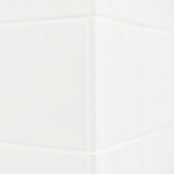 Les carreaux de céramique blanche forment un coin épuré, réfléchissant subtilement la lumière. La surface lisse suggère un décor