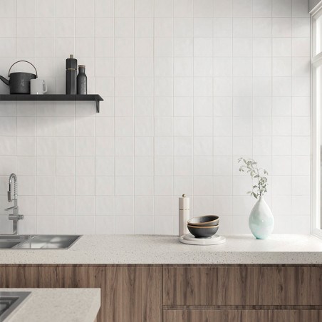 Une cuisine moderne présente des carreaux carrés blancs comme dosseret. Un comptoir contient un bol, une tasse et un vase. une é
