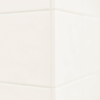 Les carreaux de céramique blanche forment un coin qui se croise, créant une structure épurée et minimaliste. Les surfaces lisses