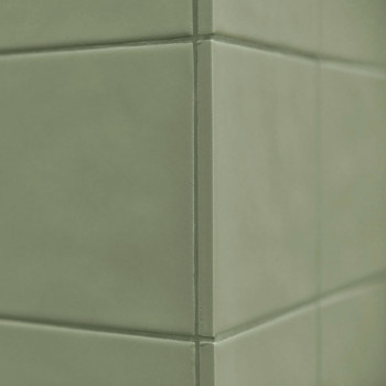 Los azulejos de cerámica verde forman una esquina, creando una superficie limpia y lisa en un ambiente interior minimalista.