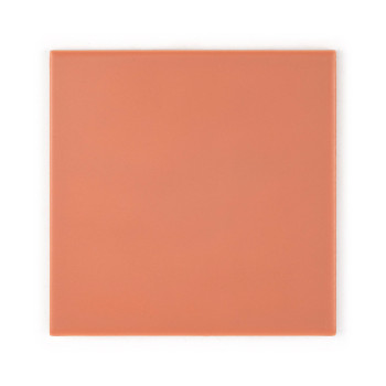 Un azulejo cerámico liso, cuadrado, de color melocotón, apoyado sobre una superficie plana, de color claro, con un sutil acabado