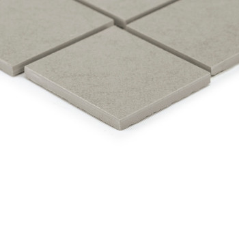 Les carreaux carrés gris reposent sur une surface lisse, un carreau chevauchant légèrement les autres, créant une disposition de