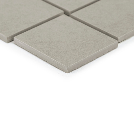 Les carreaux carrés gris reposent sur une surface lisse, un carreau chevauchant légèrement les autres, créant une disposition de