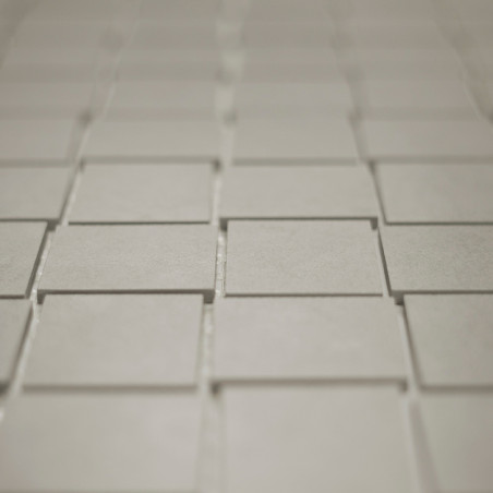 Les carreaux carrés sont disposés selon un motif de grille décalé, créant un subtil effet tridimensionnel. Les carreaux semblent