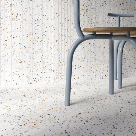 Una silla con patas de metal azul claro se apoya sobre un piso de terrazo moteado, contra una pared a juego, creando una estétic