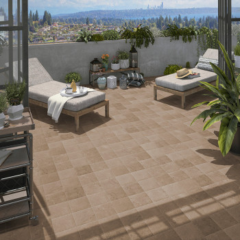 Two lounge chairs with cushions and side tables sit on a tiled terrace. Surrounded by potted plants, the scene overlooks a citys