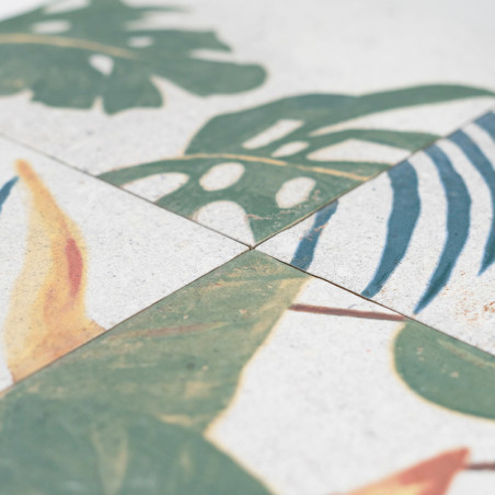Os ladrilhos cerâmicos apresentam desenhos de folhas tropicais, principalmente verdes com toques de amarelo e azul. As peças são