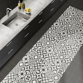 Des carreaux géométriques noirs et blancs recouvrent une partie du sol d'une cuisine à côté d'un comptoir gris moderne avec un é