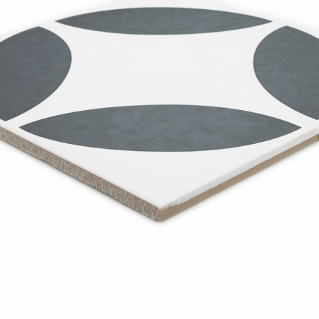 A square ceramic tile features a pattern of four dark gray quarter-circles on a white background, forming a symmetrical design.