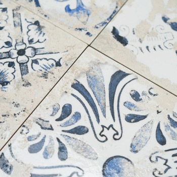 Los azulejos muestran intrincados patrones florales azules con un aspecto desgastado. Se cruzan en líneas limpias, creando un am