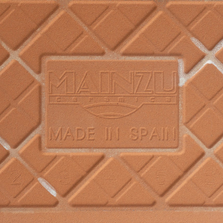 Um ladrilho cerâmico de terracota apresenta padrões de diamante em relevo e texto em relevo que diz “MAINZU ceramica” e “MADE IN