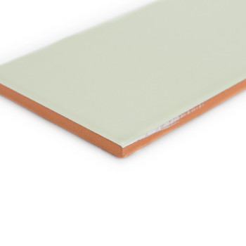 Eine rechteckige Fliese mit einer glatten, blassgrünen Oberfläche liegt flach liegend mit sichtbaren orangebraunen Kanten in ein