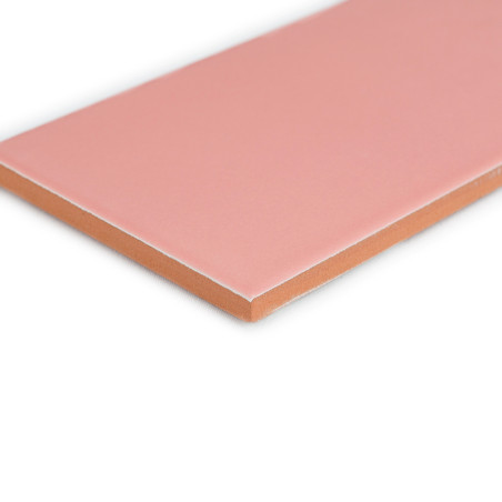 Um ladrilho retangular, liso e rosa repousa sobre um fundo branco, destacando suas bordas limpas e a parte inferior em cor terra