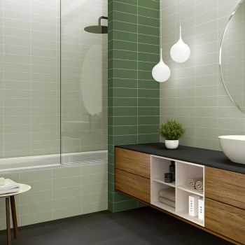 Badkamer met mintgroene wandtegels, voorzien van een wastafel op een houten wastafel, een ronde spiegel, een potplant en hanglam