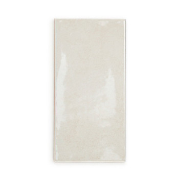 Um ladrilho cerâmico retangular bege brilhante assenta sobre um fundo branco liso, refletindo a luz sutilmente em sua superfície