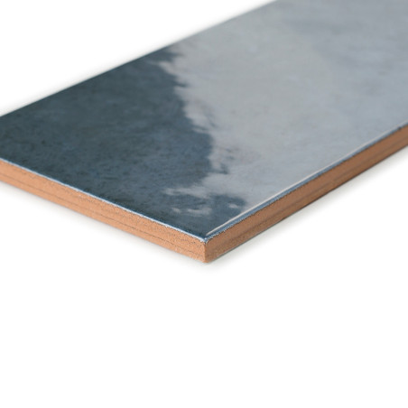 Un azulejo cerámico rectangular con una superficie brillante y reflectante que pasa del gris oscuro al gris claro. se muestra so