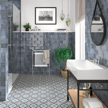 El lavabo con un diseño elegante se encuentra en un baño con azulejos estampadas, azulejos azules y plantas decorativas.