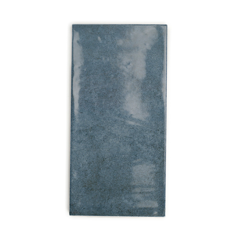 Azulejo de cerámica rectangular, que muestra una superficie brillante y opaca de color gris azulado. aparece sobre un fondo blan