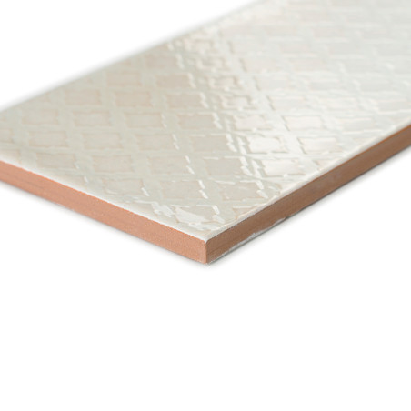 Un azulejo cerámico rectangular descansa en diagonal y presenta una superficie brillante con diseño de diamantes. Sus bordes rev