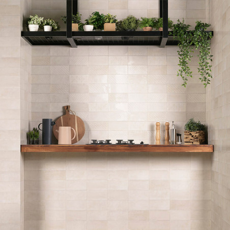Azulejos retangulares brancos formam um cenário de cozinha com uma prateleira de madeira. Na prateleira, utensílios de cozinha e