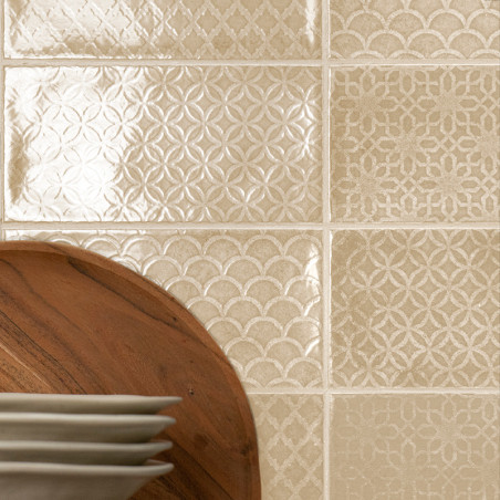 Les carreaux de céramique affichent des motifs géométriques complexes, reflétant la lumière dans une cuisine. Les assiettes repo