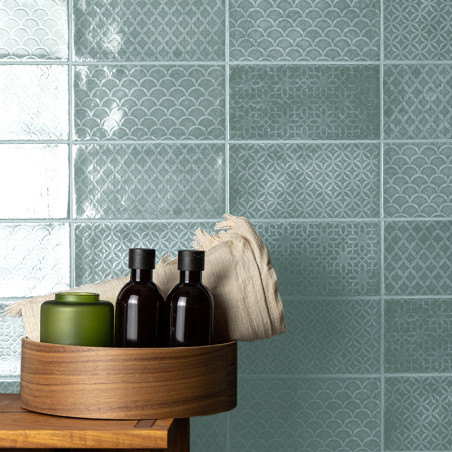 Los azulejos turquesas presentan intrincados patrones geométricos y festoneados. Una bandeja de madera contiene botellas y un pa