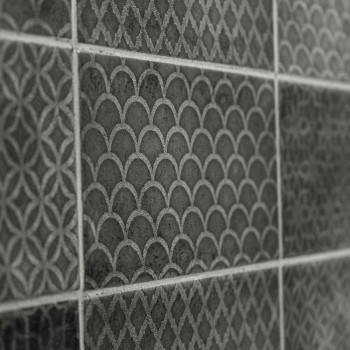Una serie de azulejos oscuros texturizados presentan patrones geométricos, que incluyen escamas y diseños de celosía, formando u