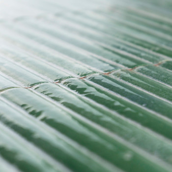 azulejos de cerámica verdes dispuestas en fila, que reflejan la luz y crean una apariencia brillante. La superficie es ligeramen