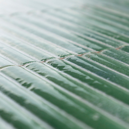 Groene keramische tegels op een rij gerangschikt, reflecterend licht en creëren een glanzend uiterlijk. Het oppervlak is enigszi