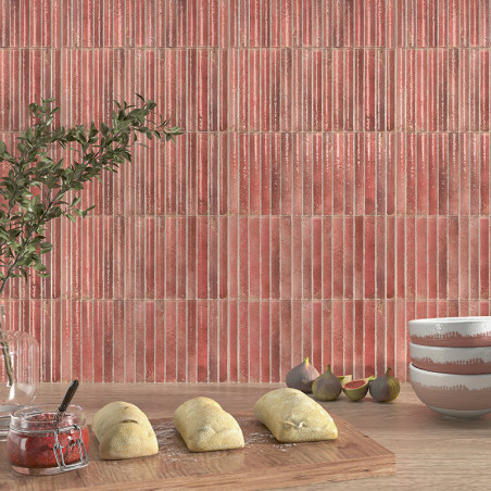 Rode verticaal gestreepte tegels creëren een achtergrond in een keuken. Op de voorgrond rust het deeg op een houten plank naast 