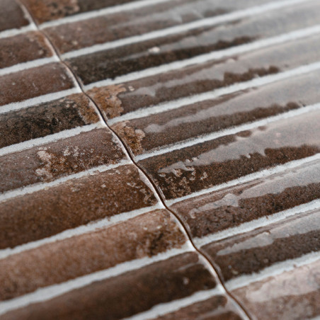 Bruine keramische tegels vertonen een glanzende, geribbelde textuur, parallel uitgelijnd met lichte kleurvariaties, waardoor een