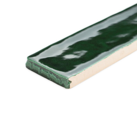 Un carreau rectangulaire vert brillant repose à plat, réfléchissant la lumière dans un motif de surface lisse, sur un fond blanc