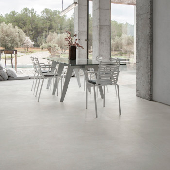 Un juego de sillas blancas rodea una mesa de comedor moderna en el interior, con grandes ventanales que ofrecen vistas a un sere