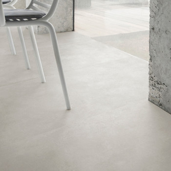 Los azulejos de color gris claro se extienden a lo largo de un espacio interior moderno, junto a las ventanas de vidrio, con las