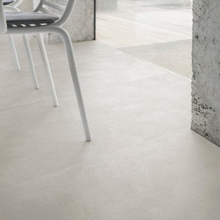 Los azulejos de color gris claro se extienden a lo largo de un espacio interior moderno, junto a las ventanas de vidrio, con las