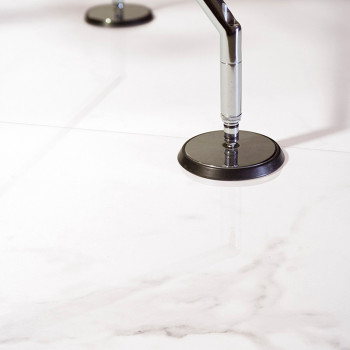 Un carreau de marbre blanc et lisse reflète deux bouchons métalliques le fixant à la surface brillante, lui conférant un design 