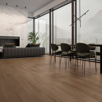 Wooden flooring spans a modern living and dining area, with a gray sofa, plants, large windows, and a contemporary light fixture