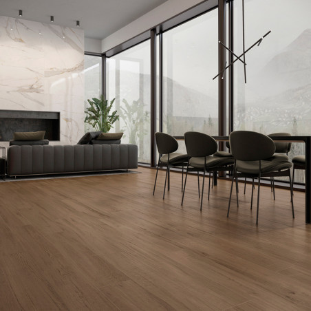 Wooden flooring spans a modern living and dining area, with a gray sofa, plants, large windows, and a contemporary light fixture