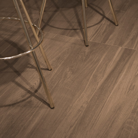 Les carreaux de céramique à texture de bois créent une esthétique chaleureuse et naturelle, où reposent les pieds de chaise en m