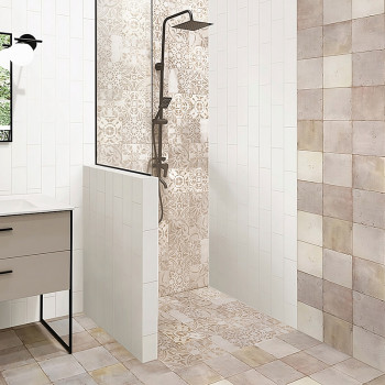A shower area with intricate beige and cream patterned tiles has a modern black shower fixture. It’s surrounded by white vertica