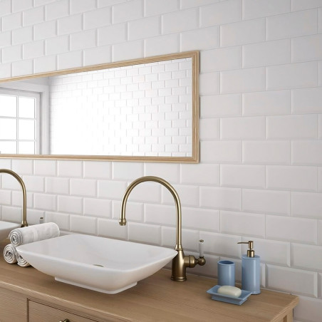 Les carreaux rectangulaires blancs créent une toile de fond épurée dans une salle de bains, avec un miroir avec cadre en bois, d