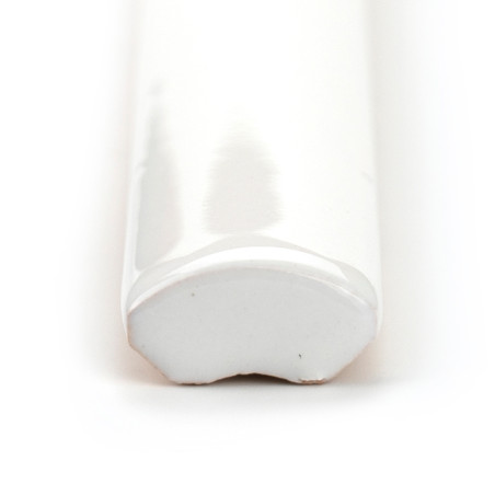Glossy white ceramic tile cap with rounded edges, lying horizontally, reflects light in a plain, minimal setting.