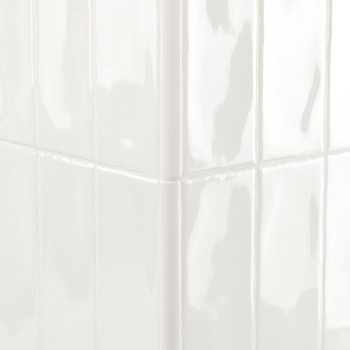 Los azulejos blancos brillantes, que reflejan la luz, forman un rincón nítido en una pared limpia y bien iluminada.