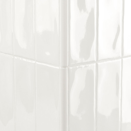 Los azulejos blancos brillantes, que reflejan la luz, forman un rincón nítido en una pared limpia y bien iluminada.