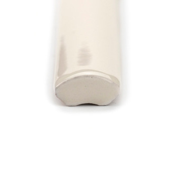 A glossy, cream-colored ceramic trim tile lies horizontally, ending in a rounded, smooth edge. Its placed on a plain white backg