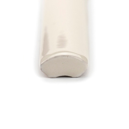 A glossy, cream-colored ceramic trim tile lies horizontally, ending in a rounded, smooth edge. Its placed on a plain white backg