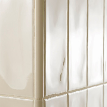Glänzende beige Fliesen mit glatter Oberfläche reihen sich in einer Ecke auf, reflektieren das Licht und sorgen für ein klares, 