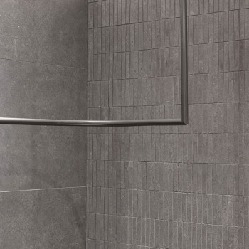Grijze rechthoekige tegels omlijnen een muur- en vloerhoek en creëren een moderne, minimalistische uitstraling. Een metalen fram